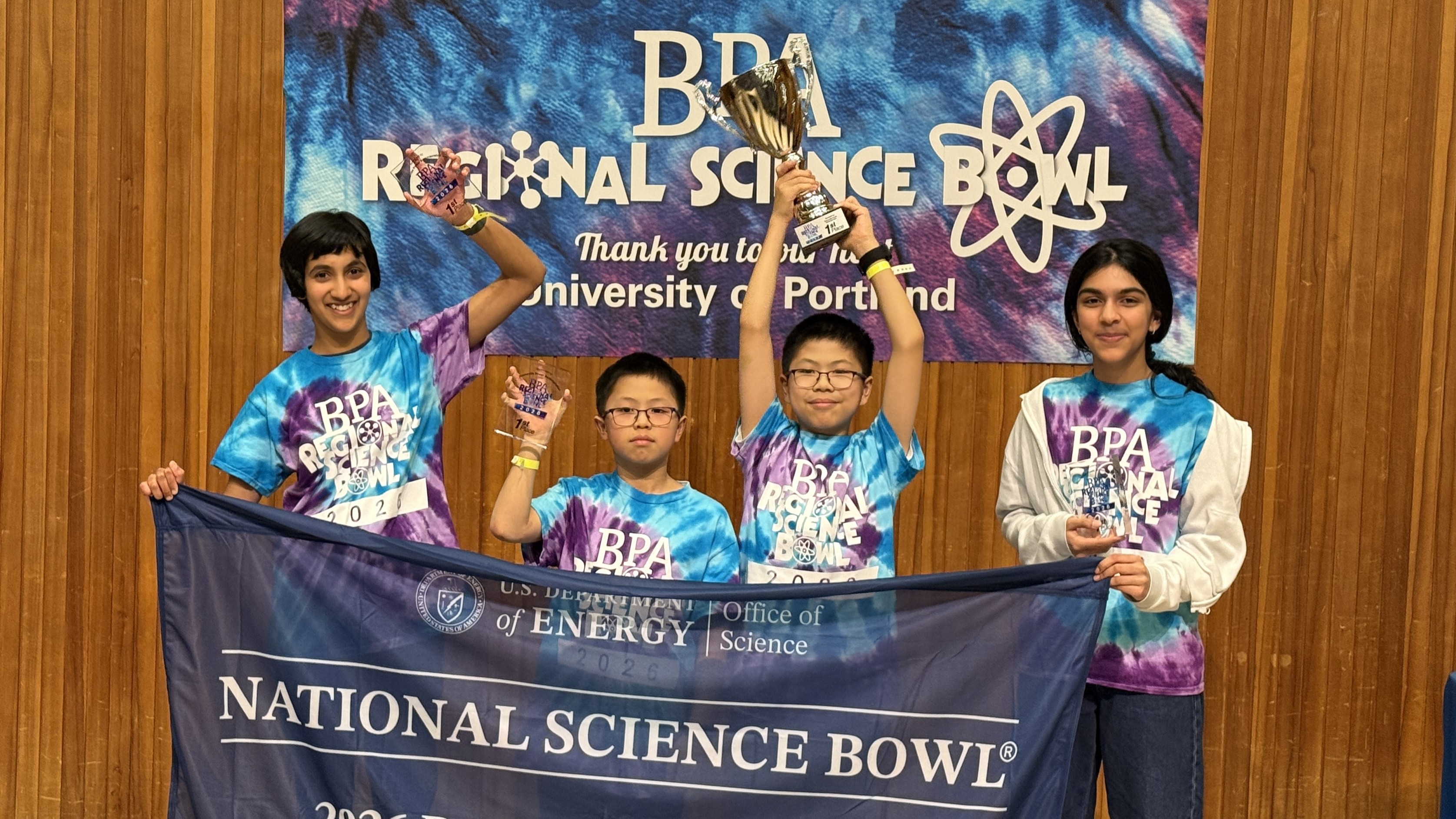 four students holding a "National Science Bowl" banner