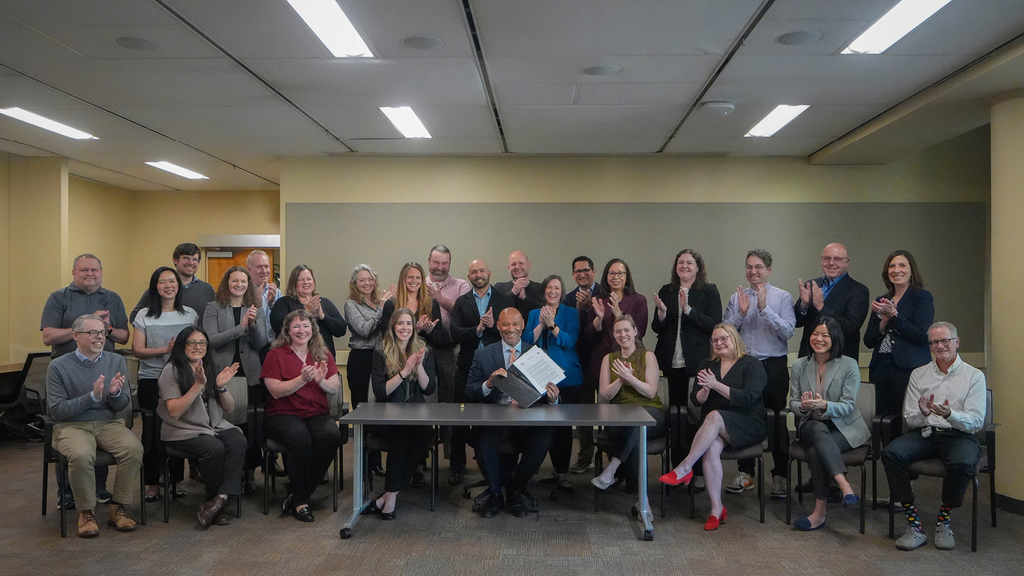 BPA Administrator John Hairston signs the Day-Ahead Markets Policy record of decision, joined by BPA staff and executives.