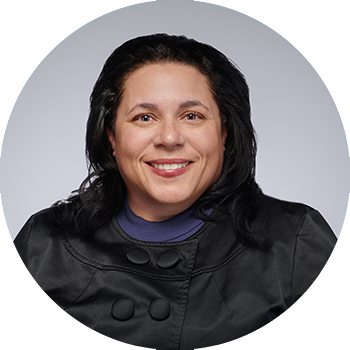 picture of woman with long dark hair, wearing a dark shirt, set against a grey background, photo in shape of circle